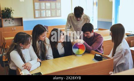 Students in physics class spin Newton's multicolored disk. Stock Photo