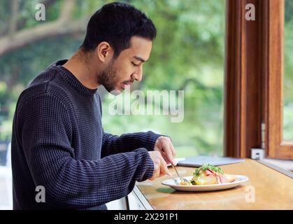 Man, eating lunch and cafe at table for health, nutrition and wellness on break from remote work. Freelance writer, person and relax in cafeteria with Stock Photo