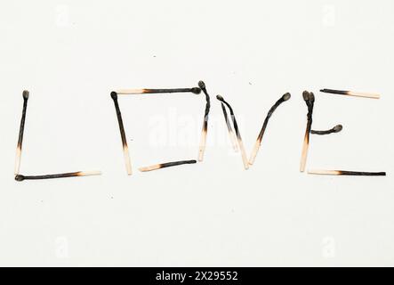 Love - an expression arranged from burnt matches on a white background. Concept. Stock Photo