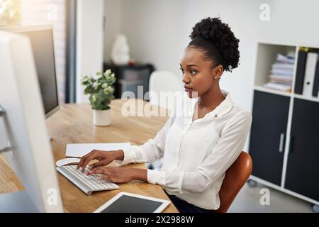 Business woman, computer and reading in office for information technology, software or online programming. African programmer or web developer typing Stock Photo