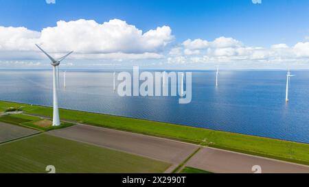 A wind farm filled with turbines in the ocean of the Netherlands, harnessing the power of the wind to generate clean energy. in the Noordoostpolder Netherlands, windmill turbines at sea Stock Photo