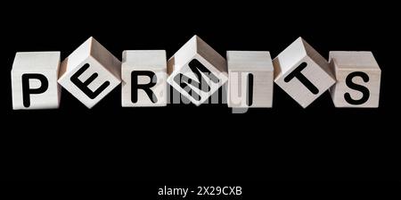 Wooden blocks with text PERMITS on black background Stock Photo