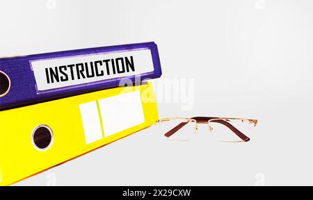 INSTRUCTIONS The word is written on a document folder with glasses on a white background. Business concept Stock Photo