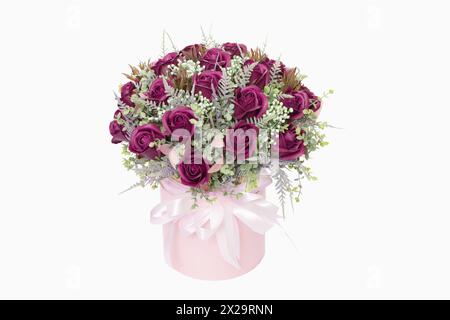 A beautiful bouquet of red roses in a pink round box with a white ribbon decorated with greenery. Valentine's Day..... Stock Photo