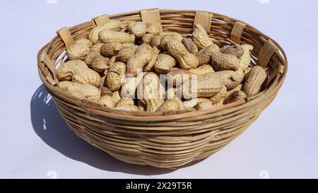 Fresh raw Groundnuts unpeeled in wicker Basket. Shelled Peanuts in heap in basket Stock Photo