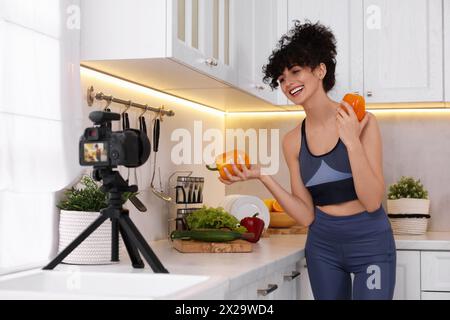 Smiling food blogger explaining something while recording video in kitchen Stock Photo