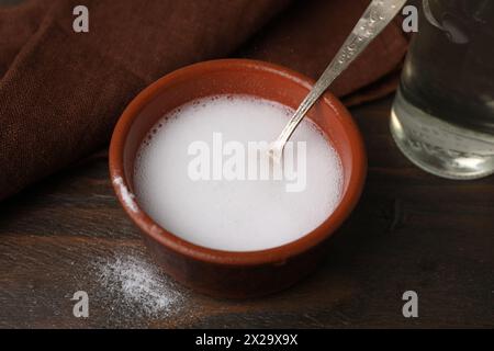 Chemical reaction of vinegar and baking soda in bowl on wooden table, closeup Stock Photo