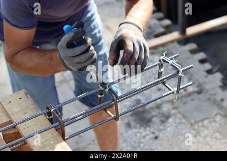 Hand holding reinforcement steel. Professional construction worker.  Close up photo of builder's hands in protective gloves. Stock Photo