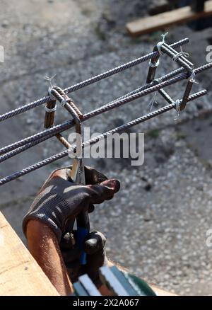 Hand holding reinforcement steel. Professional construction worker.  Close up photo of builder's hands in protective gloves. Stock Photo