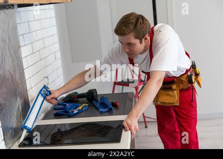 craftsman installs hob in kitchen. Household Appliance Installation Services Concept. Stock Photo