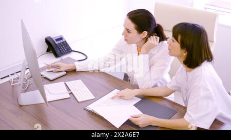 Colleagues discussing about medical report using computer in the clinic Stock Photo
