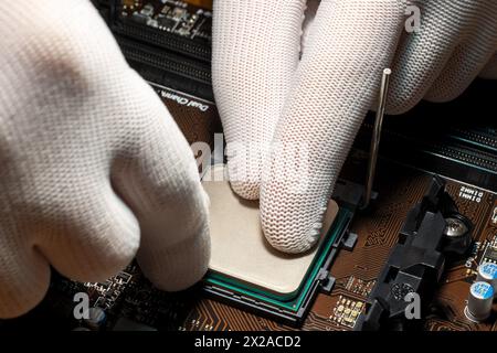 Man hands in gloves replacing processor on the computer motherboard Stock Photo