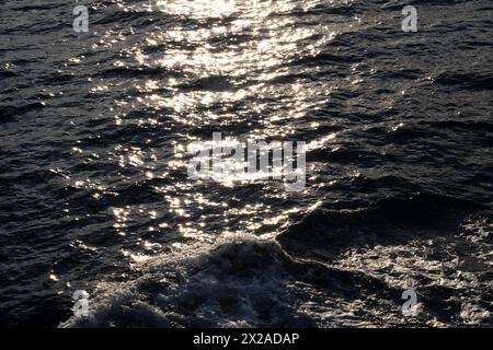 Lens star formed on water body on a sea, A calm ocean reflects sun stars in the morning light and foamy water along with waves Stock Photo