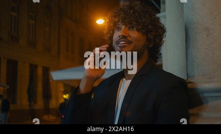 Indian Arabian Latino American man holding mobile phone telephone talking chatting communicate gossip friendship cheerful happy guy call smartphone Stock Photo
