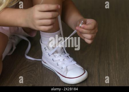 Picture of Kid tying shoes. Little girl struggling to tie shoe laces. Child ...