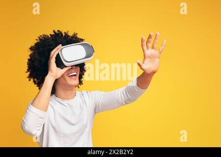 Excited black guy pushing virtual button in VR glasses Stock Photo