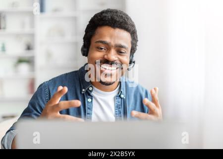Smiling black man with headset using laptop Stock Photo