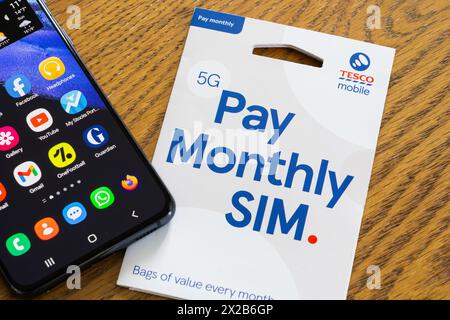 Tesco Mobile 5G pay monthly SIM pack with a replacement SIM card, the Tesco Mobile logo and a smartphone, England. Concept: supermarket mobile network Stock Photo