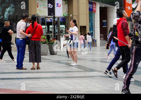 Chongqing, Chongqing Province, China, Asia, People interacting with each other in front of a shopping centre in a busy urban area Stock Photo