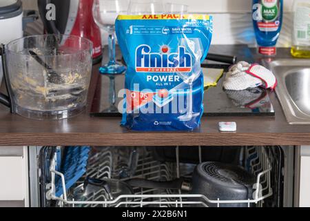 Finish Powerball Power All in 1 pack of dishwasher tablets on a kitchen surface with dirty washing up around and a dishwasher below. England Stock Photo