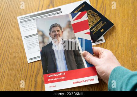 Man's hands holding a Luke Murphy Labour flier for local Basingstoke elections in May 2024, with a poll card and a passport behind. England Stock Photo