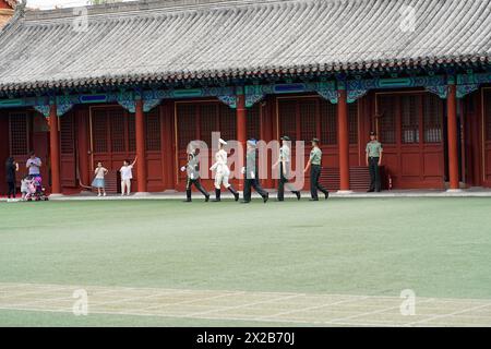 China, Beijing, Forbidden City, UNESCO World Heritage Site, A line of marching soldiers in front of traditional Chinese buildings and a red poster Stock Photo
