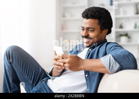 Happy black man using smartphone at home Stock Photo