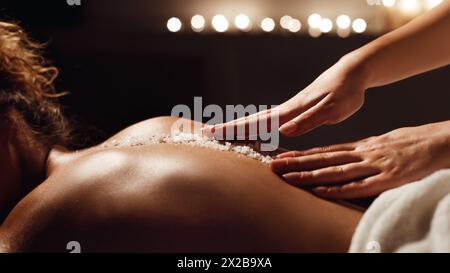African-american woman getting salt scrub treatment in spa Stock Photo
