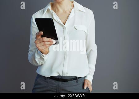 Closeup on woman worker in white blouse cloud download to smartphone from stored data on server against grey background. Stock Photo