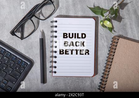 Build back better text on a notepad page on a gray background near banknotes and a magnifying glass Stock Photo