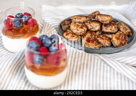 Layered berry dessert and succulent meatballs arranged on a textured cloth, creating a homestyle gastronomic scene. High quality photo Stock Photo