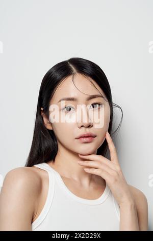 an Asian woman staring straight ahead with her hands on her chin Stock Photo