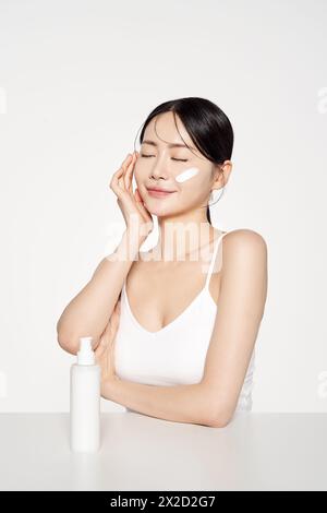 Asian Woman Poses to Apply Cosmetics to Her Face Stock Photo