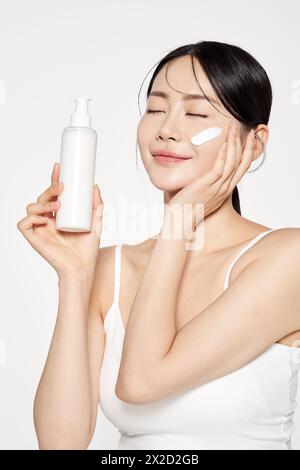 Asian Woman Poses to Apply Cosmetics to Her Face Stock Photo