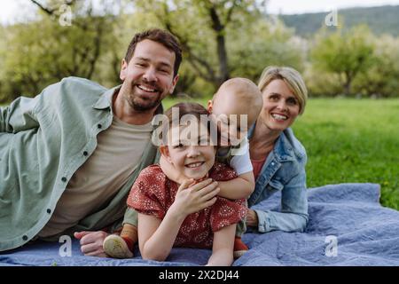 Family portrait with daughter and small toddler,, lying on picnic blanket outdoors in spring nature. Stock Photo