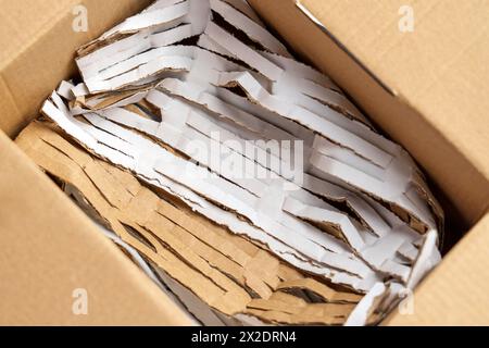 Paper cut filler in cardboard box for parcel shipments of fragile orders close up. Top view. Stock Photo