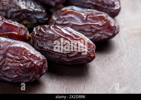Sweet organic Medjool dates with wrinkled peel on a brown wooden surface. Macro Stock Photo