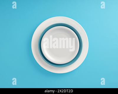 Food background. Empty ceramic white plate on blue and white plates over blue background. Stock Photo