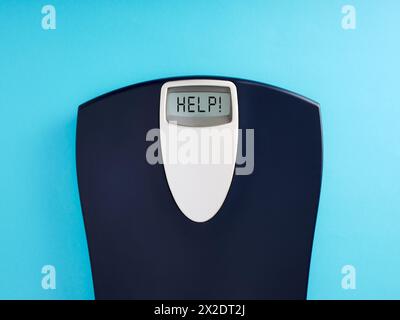 Digital bathroom scale with the word help on blue background. Dieting and healthy lifestyle concept. Top view, copy space. Stock Photo