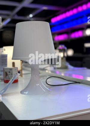 White elegant small lamp placed on a white table for display. White shiny and new small table lamp for display. Small elegant and stylish white table Stock Photo