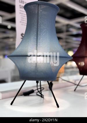 Blue fabric lighted lamp with black stand and wires. Double conical shaped small table lamp for interior. Black metallic stand to support the lamp. Stock Photo