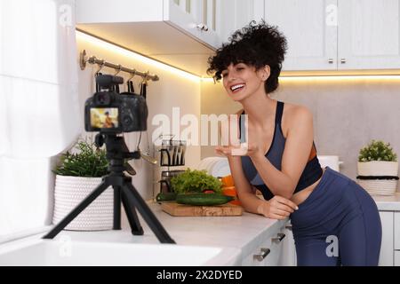 Smiling food blogger explaining something while recording video in kitchen Stock Photo