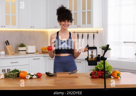 Smiling food blogger explaining something while recording video in kitchen Stock Photo
