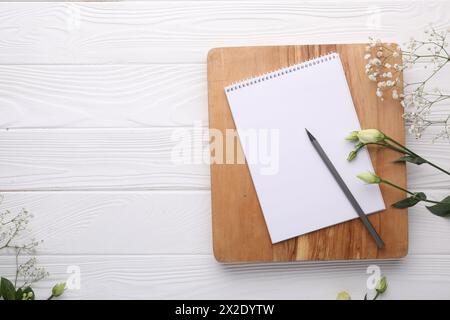 Guest list. Notebook, pencil and beautiful flowers on white wooden background, flat lay. Space for text Stock Photo