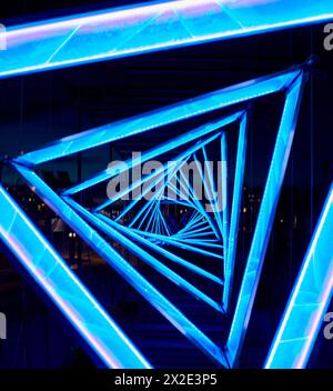 Detail of a bright triangular light blue tunnel conveys a distorted or twisted reality concept. Closeup of a light blue triangle shape passage Stock Photo