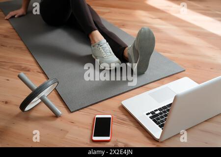 Closeup fit young woman with perfect body doing exercises at home while watching video workout classes on laptop. Practicing yoga online. Home fitness during coronavirus quarantine and self isolation Stock Photo