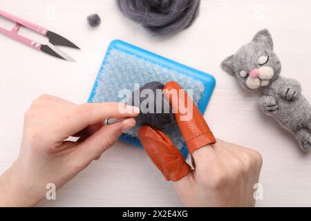 Woman felting from wool at light wooden table, top view Stock Photo