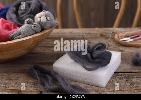 Felting tools, wool and toy cat on wooden table Stock Photo