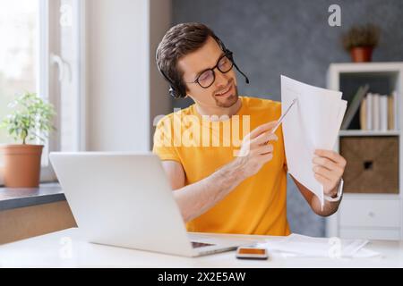 Millennial professional online tutor teacher giving online language or math class using laptop, pointing on exercise. Smiling young freelancer wearing headset, communicating with client via video call Stock Photo