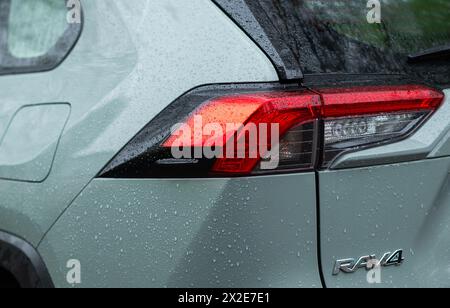 The back of a green toyota rav4 hybrid car with a sign or logo with raindrops in the park and the rear light close-up. Kyiv, Ukraine - April 2024 Stock Photo